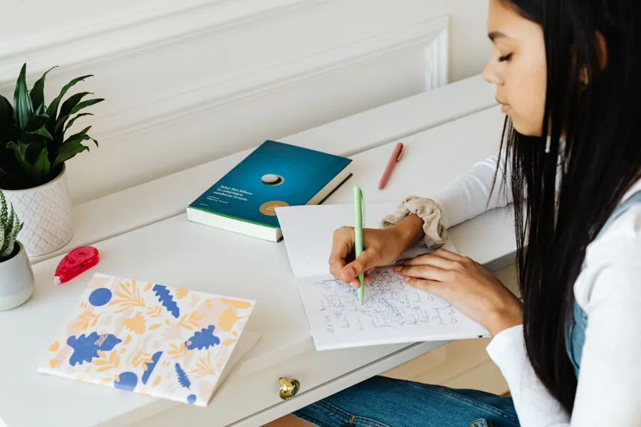 Élève révisant avec un manuel et un cahier sur un bureau