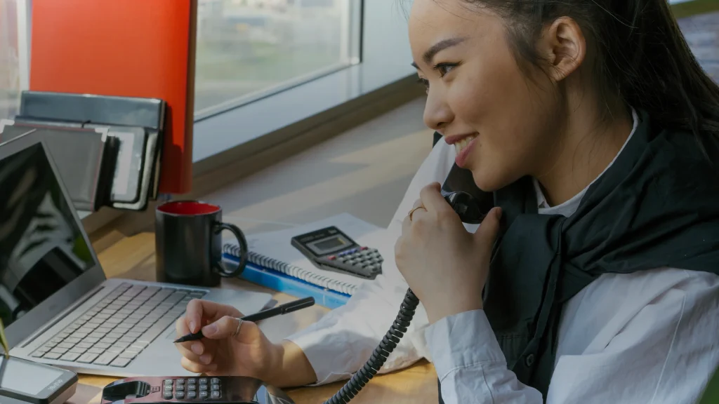 Assistante de gestion au téléphone devant son poste de travail